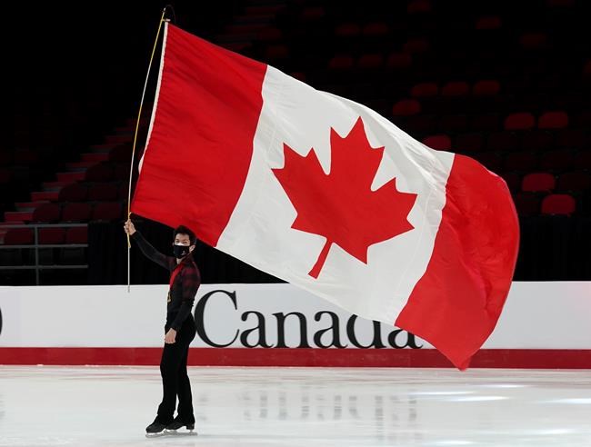 Keegan Messing skates with a Canadian flag after a medal ceremony at the National Skating Championships, Saturday, Jan. 8, 2022 in Ottawa. THE CANADIAN PRESS/Adrian Wyld