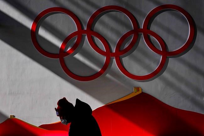 A man wears a protective mask while walking inside of the Zhangjiakou National Ski Jumping Centre before the start of competition at the 2022 Winter Olympics, Wednesday, Feb. 2, 2022, in Zhangjiakou, China. (AP Photo/Matthias Schrader)