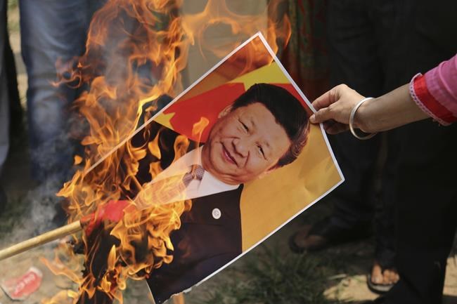 FILE-A Bharatiya Janata Party activist burns a photograph of Chinese President Xi Jinping during a protest in Jammu, India, Wednesday, July 1, 2020. India will not attend Friday's opening ceremony of the Beijing Winter Olympics, after one of the torchbearers reportedly chosen by Chinese authorities riled up New Delhi's anger. India's foreign affairs spokesman Arindam Bagchi on Thursday said it was