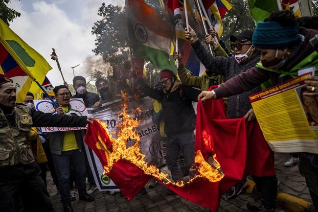 Exile Tibetans burn a Chinese flag during a protest against Beijing Olympic Games in New Delhi, India, Friday, Feb. 4, 2022. Hundreds of Tibetan exiles are marching outside the Chinese Embassy in New Delhi, denouncing the Beijing Winter Olympics and demanding freedom for their region. (AP Photo/Altaf Qadri)