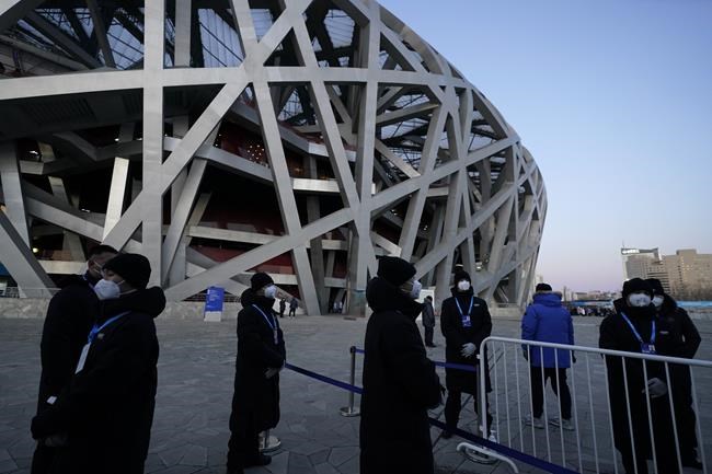 Security stand outside the National Stadium known as the Bird's Nest ahead of the opening ceremony of the 2022 Winter Olympics, Friday, Feb. 4, 2022, in Beijing. (AP Photo/Jae C. Hong)