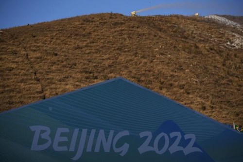 A snow making machine blows snow on a hill overlooking cross-country skiing practice before the 2022 Winter Olympics, Wednesday, Feb. 2, 2022, in Zhangjiakou, China. (AP Photo/Aaron Favila)