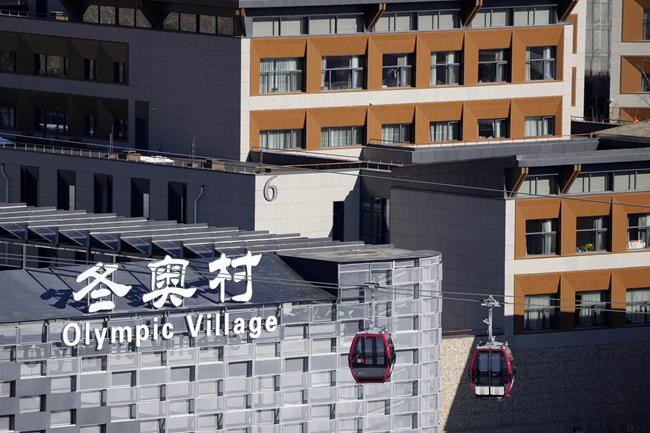 Gondolas glide past the Olympic Village at the 2022 Winter Olympics, Wednesday, Feb. 2, 2022, in the Yanqing district of Beijing. (AP Photo/Mark Schiefelbein)