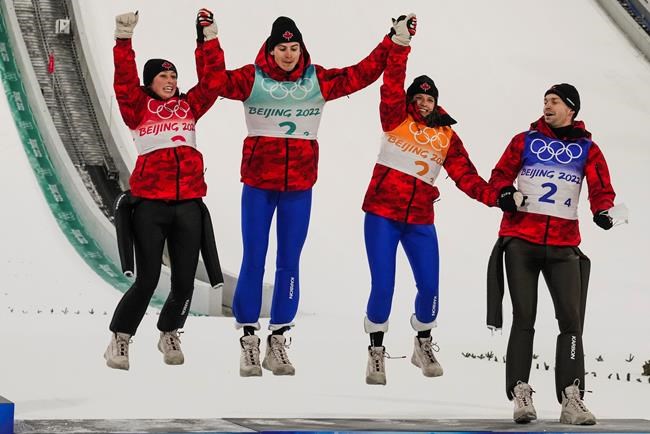 Canada's Alexandria Loutitt, left, celebrates with teammates Matthew Soukup, Abigail Strate and Mackenzie Boyd-Clowes during the the venue ceremony after winning a bronze in the ski jumping mixed team event at the 2022 Winter Olympics, Monday, Feb. 7, 2022, in Zhangjiakou, China. THE CANADIAN PRESS/AP/Matthias Schrader