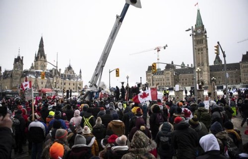People listen to a sermon delivered by a pastor from the back of a flatbed truck parked on Wellington Street in front of Parliament Hill as a protest against COVID-19 restrictions that has been marked by gridlock and the sound of truck horns continues into its second week, in Ottawa, on Sunday, Feb. 6, 2022. Sixty two per cent of Canadians oppose the Freedom Convoy protests, with 44 per cent saying they strongly object to them, according to a Leger poll. THE CANADIAN PRESS/Justin Tang