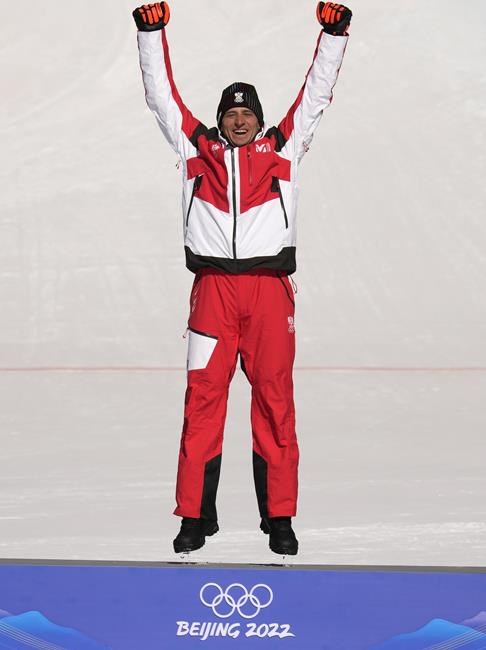 Matthias Mayer of Austria jumps on the podium before receiving his gold medal during the medal ceremony for the men's super-G at the 2022 Winter Olympics, Tuesday, Feb. 8, 2022, in the Yanqing district of Beijing. (AP Photo/Luca Bruno)