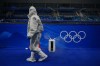 A person in protective gear walks by an air purifier after emptying water at the curling venue ahead of the Beijing Winter Olympics Tuesday, Feb. 1, 2022, in Beijing. (AP Photo/Brynn Anderson)