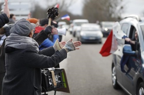 People applaud a convoy departing for Paris, Friday, Feb.11, 2022 in Strasbourg, eastern France. Authorities in France and Belgium have banned road blockades threatened by groups organizing online against COVID-19 restrictions. The events are in part inspired by protesters in Canada. Citing 