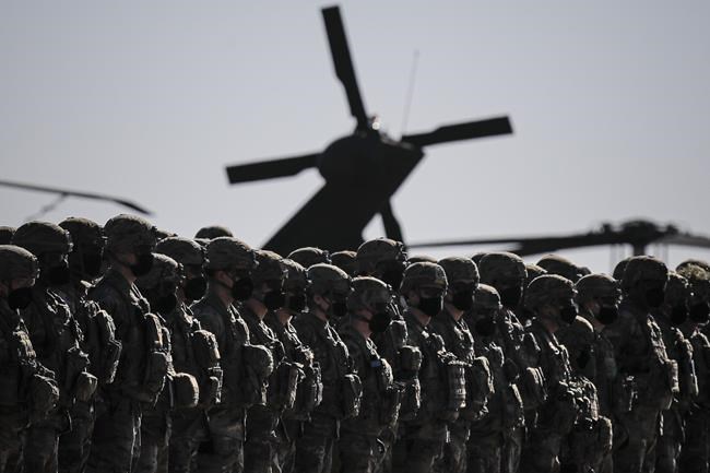 US soldiers line up during the visit of NATO Secretary General Jens Stoltenberg at the Mihail Kogalniceanu airbase, near the Black Sea port city of Constanta, eastern Romania, Friday, Feb. 11, 2022. Stoltenberg paid an official visit to Romania on Friday, where he joined the country's president Klaus Iohannis at a military airbase that will host some of the 1,000 U.S. troops deployed to the country as the alliance bolsters its forces on the eastern flank as tensions soar between Russia and Ukraine. (AP Photo/Andreea Alexandru)