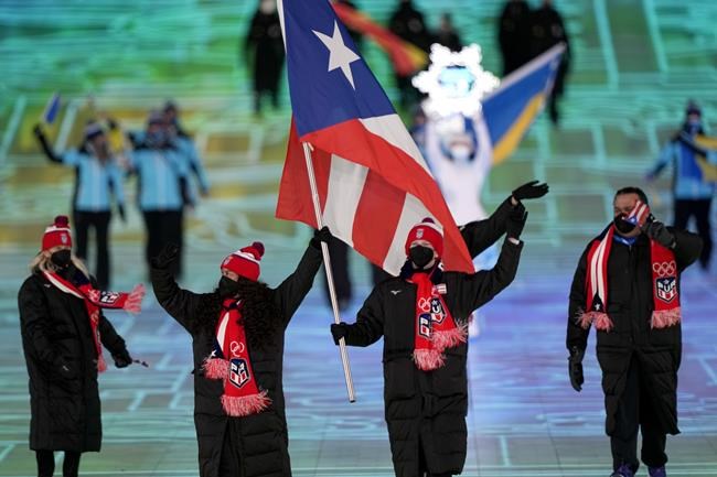 Kellie Delka and William C. Flaherty, of Puerto Rico, lead their team in during the opening ceremony of the 2022 Winter Olympics, Friday, Feb. 4, 2022, in Beijing. (AP Photo/David J. Phillip)
