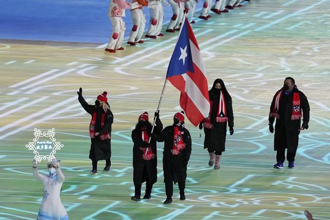 Kellie Delka and William C. Flaherty, of Puerto Rico, carry their country's flag during the opening ceremony of the 2022 Winter Olympics, Friday, Feb. 4, 2022, in Beijing. (AP Photo/Bernat Armangue)