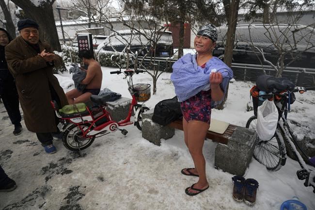 A woman dries herself after a swim in the half-frozen waters of the Shichahai Lake in Beijing, Sunday, Feb. 13, 2022. As the Winter Olympics carry on just a short distance away inside the bubble, Beijing residents are enjoying their own traditional winter games by the lake situated in Xicheng district. (AP Photo/Andy Wong)