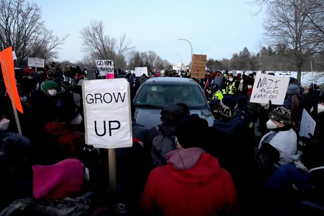 Residents surround a couple in a pick up truck as a police officer tries to negotiate their release from a counter protest on Riverside Drive, after residents prevented vehicles from driving in a convoy to Parliament Hill, on the 17th day of a protest against COVID-19 measures that has grown into a broader anti-government protest, in Ottawa, Sunday, Feb. 13, 2022. THE CANADIAN PRESS/Justin Tang