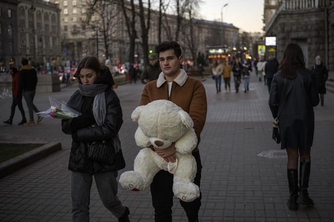 Pedestrians walk along a street in downtown Kyiv, Ukraine, Monday, Feb. 14, 2022. More NATO troops headed to Eastern Europe and some nations worked to move their citizens and diplomats out of Ukraine on Monday, as Germany's chancellor made a last-ditch attempt to head off a feared Russian invasion that some warn could be just days away. (AP Photo/Emilio Morenatti)