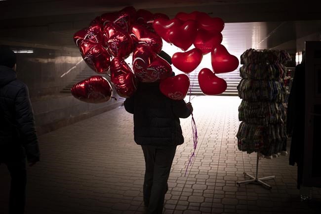 A vendor walks holding red heart-shaped balloons in downtown Kyiv, Ukraine, Monday, Feb. 14, 2022. More NATO troops headed to Eastern Europe and some nations worked to move their citizens and diplomats out of Ukraine on Monday, as Germany's chancellor made a last-ditch attempt to head off a feared Russian invasion that some warn could be just days away. (AP Photo/Emilio Morenatti)