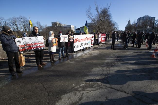 Demonstrators hold anti-Putin's poster during a picket while Ukrainian President Volodymyr Zelenskyy German and chancellor Olaf Scholz have talks at The Mariinskyi Palace in Kyiv, Ukraine, Monday, Feb. 14, 2022. German Chancellor Olaf Scholz visited Ukraine as part of a flurry of Western diplomacy aimed at heading off a feared Russian invasion that some warn could be just days away. (AP Photo)
