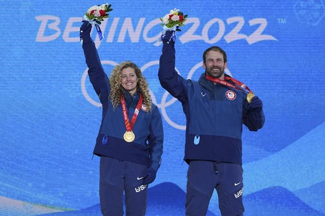 Gold medalists United States' Lindsey Jacobellis and Nick Baumgartner celebrates during a medal ceremony for the mixed team snowboard cross at the 2022 Winter Olympics, Saturday, Feb. 12, 2022, in Zhangjiakou, China. (AP Photo/Gregory Bull)