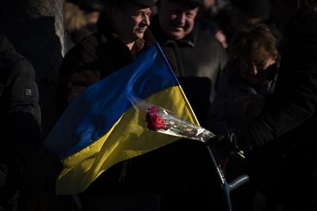 People attend a ceremony to mark the anniversary of the withdrawal of Soviet troops from Afghanistan in the city of Kyiv, Ukraine, Tuesday, Feb. 15, 2022. Russia says that some units participating in military exercises will begin returning to their bases. That adds to glimmers of hope that the Kremlin may not be planning to invade Ukraine imminently. (AP Photo/Emilio Morenatti)