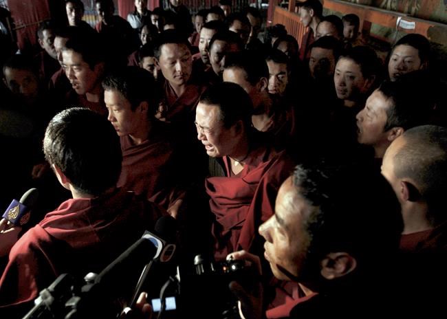 FILE - A Tibetan Buddhist monk, center, cries while he saw foreign journalists visit to the Jokhang Temple, one of Tibet's holiest shrines in Lhasa, capital of China's Tibet Autonomous Region Thursday, March 27, 2008. Ahead of the Beijing summer Olympics 14 years ago, deadly demonstrations erupted across the Tibetan plateau. But now Tibet has fallen silent, even as the Olympic games come to Beijing again. (AP Photo/Andy Wong, File)