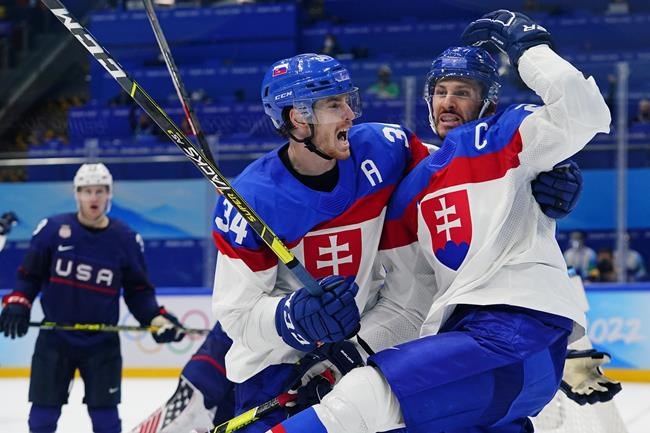 Slovakia's Marek Hrivikl, right, is hugged by Peter Cehlarik (34) after Hrivikl scored a goal against the United States during a men's quarterfinal hockey game at the 2022 Winter Olympics, Wednesday, Feb. 16, 2022, in Beijing. (AP Photo/Matt Slocum)