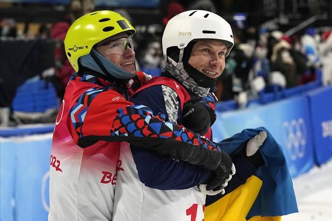 Bronze medal winner Ilia Burov, of the Russian Olympic Committee, left, hugs silver medal winner Ukraine's Oleksandr Abramenko as they celebrate after the men's aerials finals at the 2022 Winter Olympics, Wednesday, Feb. 16, 2022, in Zhangjiakou, China. (AP Photo/Gregory Bull)
