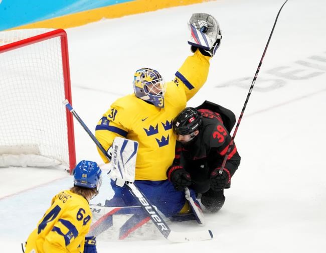 Team Sweden goaltender Lars Johansson (31) makes a save as Team Canada forward Landon Ferraro (39) slides into him and Sweden defenceman Jonathan Pudas (64) looks on during second period men's quarter-final hockey action at the Beijing Winter Olympics in Beijing, China, on Wednesday, Feb. 16, 2022. THE CANADIAN PRESS/Ryan Remiorz
