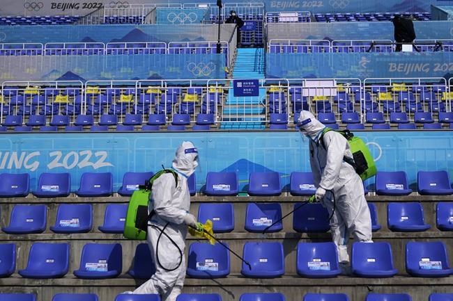 Workers in protective gear disinfect seats following the men's freestyle skiing big air finals of the 2022 Winter Olympics, Wednesday, Feb. 9, 2022, in Beijing. THE CANADIAN PRESS/AP/Jae C. Hong
