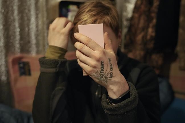 A Ukrainian servicewoman checks her looks in a mirror at a frontline position outside Popasna, the Luhansk region, in eastern Ukraine, Wednesday, Feb. 16, 2022. Ukrainians defied pressure from Moscow with a national show of flag-waving unity Wednesday, while the West warned that it saw no sign of a promised pullback of Russian troops from Ukraine's borders despite Kremlin declarations of a withdrawal. (AP Photo/Vadim Ghirda)