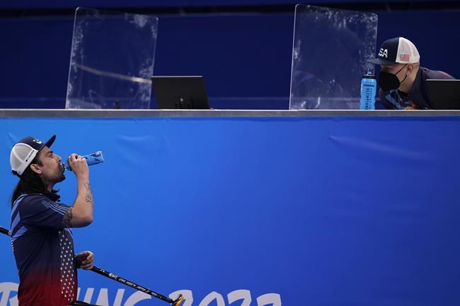 A team official speaks with United States' Christopher Plys during the men's curling semifinal match between Britain and the United States at the Beijing Winter Olympics Thursday, Feb. 17, 2022, in Beijing. The British and U.S. teams employ performance analysts who sit at the end of the ice sheet filming the action for match intelligence. The goal: to get a better picture of each side's strengths and weaknesses — information that can be relayed to players during breaks. (AP Photo/Brynn Anderson)