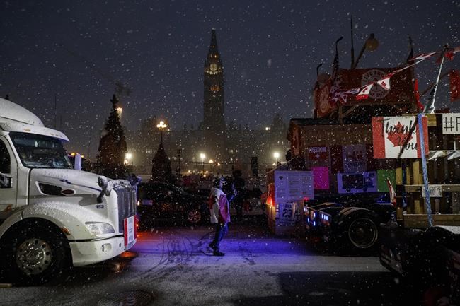Protestors and supporters walk amongst trucks as they gather during a protest against COVID-19 measures that has grown into a broader anti-government protest continues to occupy downtown Ottawa on Thursday, Feb. 17, 2022. THE CANADIAN PRESS/Cole Burston