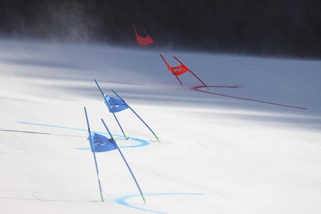 Gate flags bend in the wind after high winds caused a delay in the start of the mixed team parallel skiing event at the 2022 Winter Olympics, Saturday, Feb. 19, 2022, in the Yanqing district of Beijing. (AP Photo/Alessandro Trovati)
