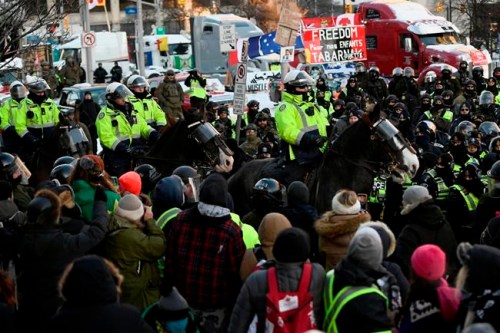 Toronto Police mounted unit charges the crowd in a dispersion tactic as police take action to put an end to a protest, which started in opposition to mandatory COVID-19 vaccine mandates and grew into a broader anti-government demonstration and occupation, in Ottawa, Friday, Feb. 18, 2022. THE CANADIAN PRESS/Justin Tang