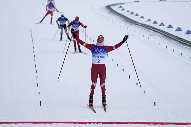 Russian athlete Alexander Bolshunov reacts as he nears the finish line during the men's weather-shortened 50km mass start free cross-country skiing competition at the 2022 Winter Olympics, Saturday, Feb. 19, 2022, in Zhangjiakou, China. (AP Photo/Alessandra Tarantino)