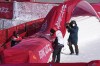 Course workers attempt to fix signage to the safety barriers in the finish area for the mixed team parallel skiing event after it was delayed due to high winds at the 2022 Winter Olympics, Saturday, Feb. 19, 2022, in the Yanqing district of Beijing. (AP Photo/Luca Bruno)