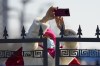 A woman outside the fenced off closed-loop area for the Olympics takes a picture of the Olympic Green ahead of the 2022 Winter Olympics, Feb. 1, 2022, in Beijing. (AP Photo/Natacha Pisarenko)