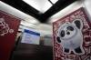 Inside an elevator shows a poster of Bing Dwen Dwen, the Beijing Winter Olympics mascot and a camera at the curling venue ahead of the Beijing Winter Olympics Tuesday, Feb. 1, 2022, in Beijing. (AP Photo/Brynn Anderson)