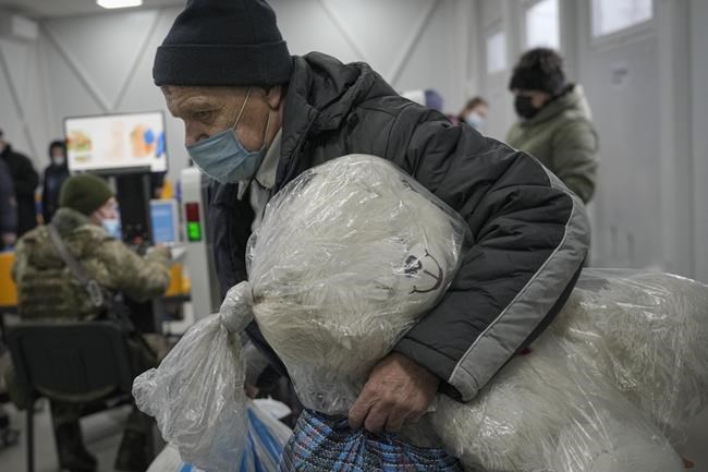 A man holds a giant stuffed toy while crossing from Ukrainian government controlled areas to pro-Russian separatists' controlled territory, in Stanytsia Luhanska, the only crossing point open daily, in the Luhansk region, eastern Ukraine, Tuesday, Feb. 22, 2022. Russia says its recognition of independence for areas in eastern Ukraine extends to territory currently held by Ukrainian forces. The statement Tuesday further raises the stakes amid Western fears that Moscow could follow up to Monday’s recognition of rebel regions with a full-fledged invasion of Ukraine. (AP Photo/Vadim Ghirda)