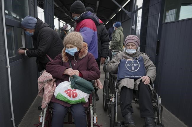 People wait to cross from Ukrainian government controlled areas to pro-Russian separatists controlled territory in Stanytsia Luhanska, the only crossing point open daily, in the Luhansk region, eastern Ukraine, Tuesday, Feb. 22, 2022. Russian lawmakers on Tuesday authorized President Vladimir Putin to use military force outside the country — a move that could presage a broader attack on Ukraine after the U.S. said an invasion was already underway there. (AP Photo/Vadim Ghirda)