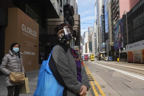 People wearing face masks walk at a downtown street in Hong Kong Wednesday, Feb. 23, 2022. Hong Kong residents are becoming increasingly annoyed with the administration’s insistence on sticking to China's “zero-COVID” strategy as the city posted another record number of new cases Wednesday, bristling at ever-stricter regulations and a plan to test every city resident for the virus.(AP Photo/Vincent Yu)