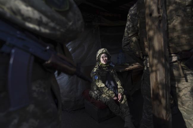 A Ukrainian soldier talks with her comrades sitting in a shelter at the line of separation between Ukraine-held territory and rebel-held territory near Svitlodarsk, eastern Ukraine, Wednesday, Feb. 23, 2022. U.S. President Joe Biden announced the U.S. was ordering heavy financial sanctions against Russia, declaring that Moscow had flagrantly violated international law in what he called the