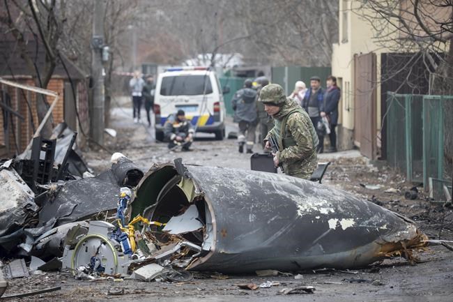 A Ukrainian Army soldier inspects fragments of a downed aircraft in Kyiv, Ukraine, Friday, Feb. 25, 2022. It was unclear what aircraft crashed and what brought it down amid the Russian invasion in Ukraine. THE CANADIAN PRESS/AP/Vadim Zamirovsky