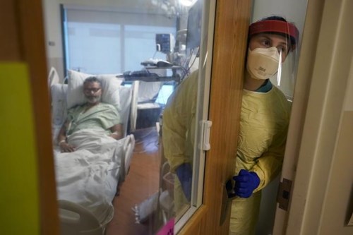 FILE - Registered nurse Rachel Chamberlin steps out of an isolation room where Fred Rutherford recovers from COVID-19 at the Dartmouth-Hitchcock Medical Center, in Lebanon, N.H., Monday, Jan. 3, 2022. The official global death toll from COVID-19 is on the verge of eclipsing 6 million — underscoring that the pandemic, now in its third year, is far from over. (AP Photo/Steven Senne, File)
