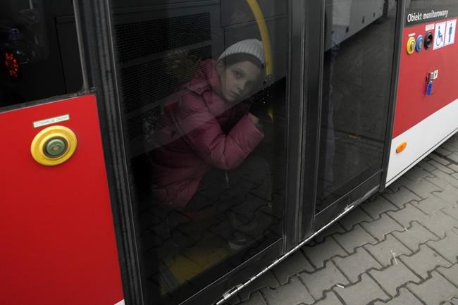 A young girl who fled the war in Ukraine sits on a bus to leave Korczowa border crossing, Poland, Sunday, March 6, 2022. The number of Ukrainians forced from their country increased to 1.5 million and the Kremlin's rhetoric grew, with Russian President Vladimir Putin warning that Ukrainian statehood is in jeopardy. He likened the West's sanctions on Russia to
