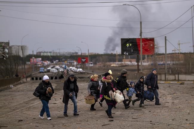 A Ukrainian police officer helps people as artillery echoes nearby while fleeing Irpin in the outskirts of Kyiv, Ukraine, Monday, March 7, 2022. Russia announced yet another cease-fire and a handful of humanitarian corridors to allow civilians to flee Ukraine. Previous such measures have fallen apart and Moscow’s armed forces continued to pummel some Ukrainian cities with rockets Monday. (AP Photo/Emilio Morenatti)