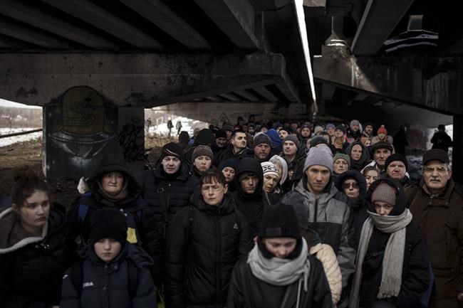 Ukrainians crowd under a destroyed bridge as they try to flee crossing the Irpin river in the outskirts of Kyiv, Ukraine, Tuesday, March 8, 2022. (AP Photo/Felipe Dana)