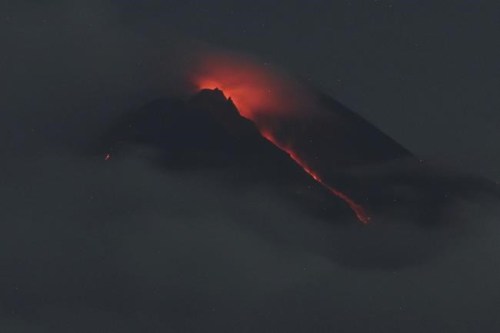 Lava flows down from the crater of Mount Merapi seen from Pakembinangun village in Sleman, Central Java, Thursday, March 10, 2022. Indonesia's Mount Merapi volcano spewed avalanches of hot clouds in eruptions overnight Thursday that forced about 250 residents to flee to temporary shelters. No casualties were reported. (AP Photo/Ranto Kresek)