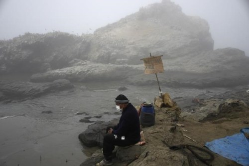 FILE - Fisherman Walter de la Cruz sits on the shore of the oil-stained Cavero Beach, unable to fish after a spill in the Ventanilla district of Callao, Peru, Jan. 21, 2022. De la Cruz, 60, is one of more than 2,500 fishermen whose livelihoods have been cast into doubt as a result of a large crude-oil spill by the Spanish-owned Repsol oil refinery on Jan. 15. (AP Photo/Martin Mejia, File)