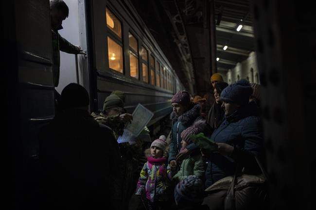 Displaced Ukrainians queue to board a Poland bound train in Lviv, western Ukraine, Sunday, March 13, 2022. Lviv in western Ukraine itself so far has been spared the scale of destruction unfolding to its east and south. The city's population of 721,000 has swelled during the war with residents escaping bombarded population centers and as a waystation for the nearly 2.6 million people who have fled the country. (AP Photo/Bernat Armangue)