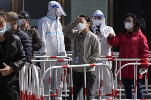 Workers line up for COVID test outside an office building on Monday, March 14, 2022, in Beijing. Chinese authorities reported more than 1,300 locally transmitted cases of COVID-19 across dozens of mainland cities Monday as the fast-spreading variant commonly known as 