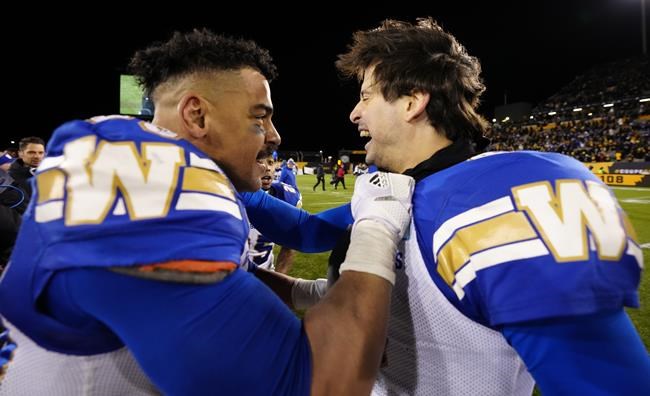 Winnipeg Blue Bombers running back Andrew Harris (33) celebrates with quarterback Zach Collaros (8) after they defeated the Hamilton Tiger-Cats in the 108th CFL Grey Cup in Hamilton, Ont., on Sunday, Dec. 12, 2021. The Manitoba Liberal Party has been told to stop selling merchandise with a
